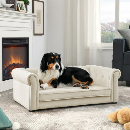Dog sitting on a small beige sofa in a living room with a fireplace and window in the background.