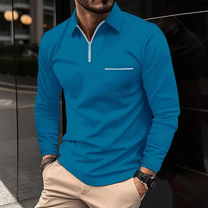 Man wearing a blue long-sleeve shirt with a zipper and pocket, standing against a reflective surface.