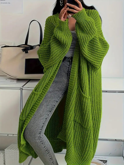 Person wearing a green knitted cardigan with a neutral background
