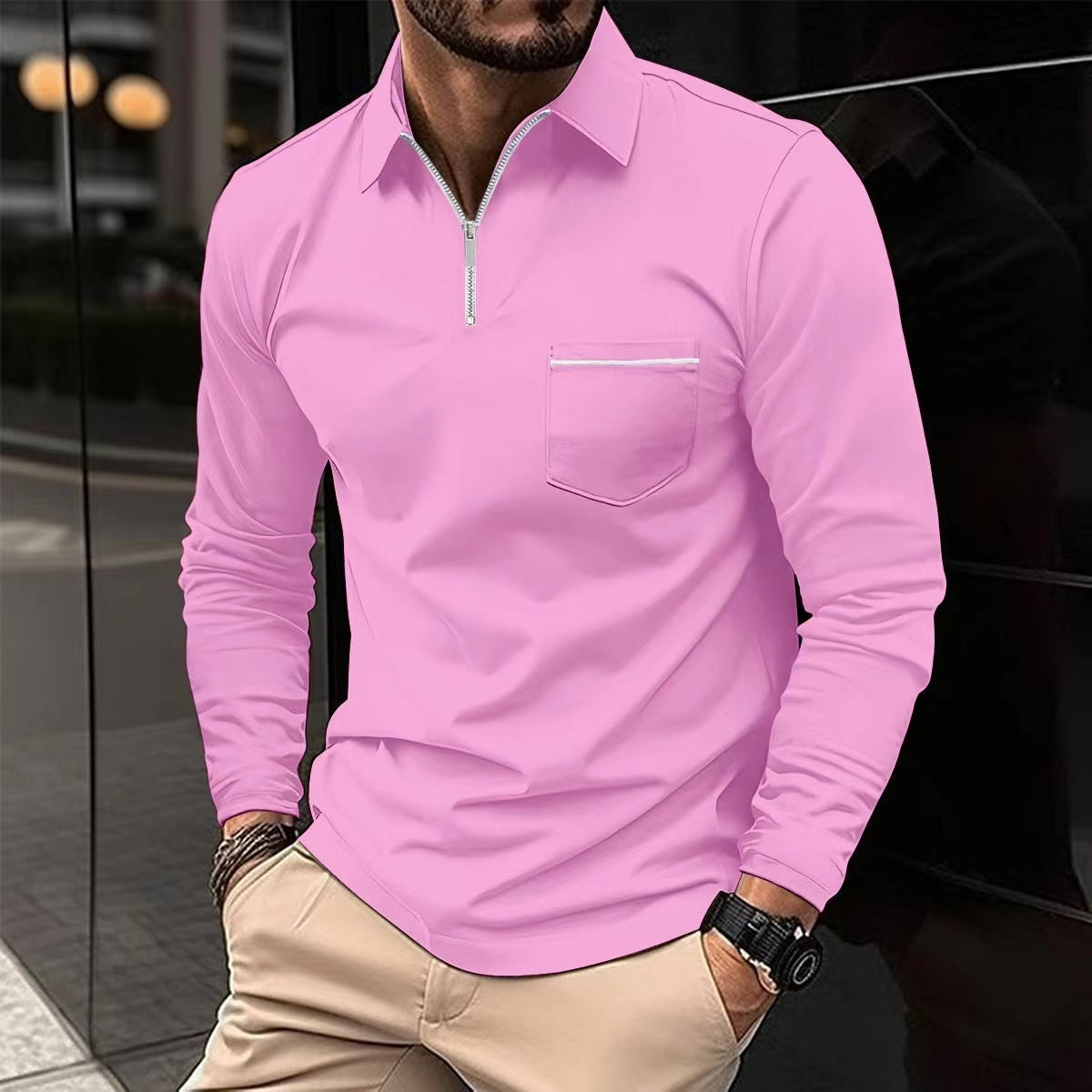 Man wearing a pink long-sleeve shirt with a zipper and pocket, standing against a reflective surface.