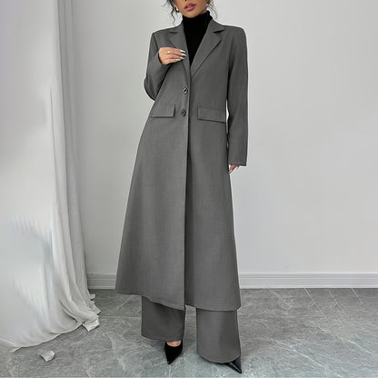 Person wearing a long gray coat and pants in a minimalistic setting