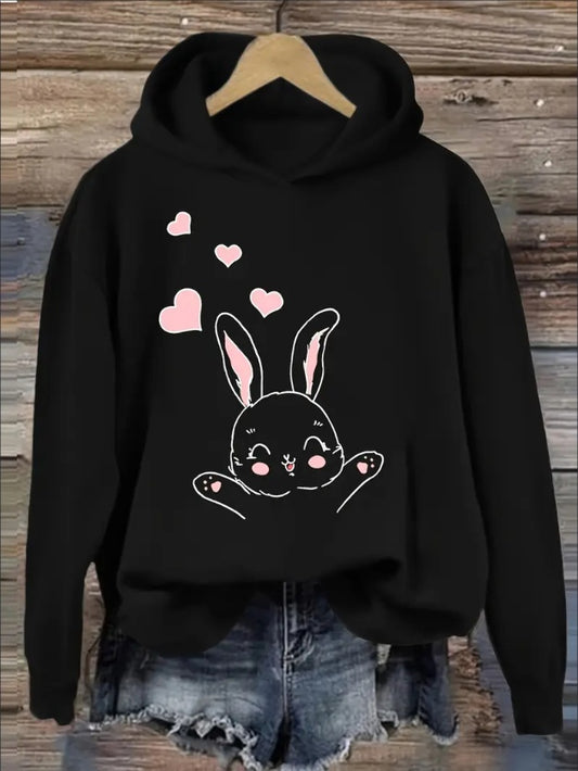 Black hoodie with a bunny design and pink hearts on a wooden background