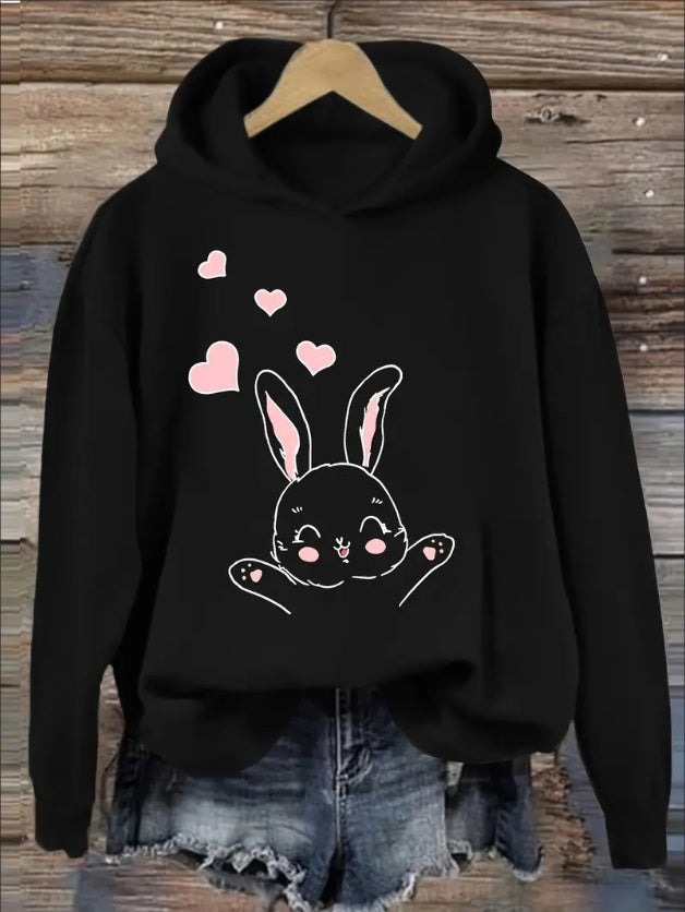Black hoodie with a bunny design and pink hearts on a wooden background