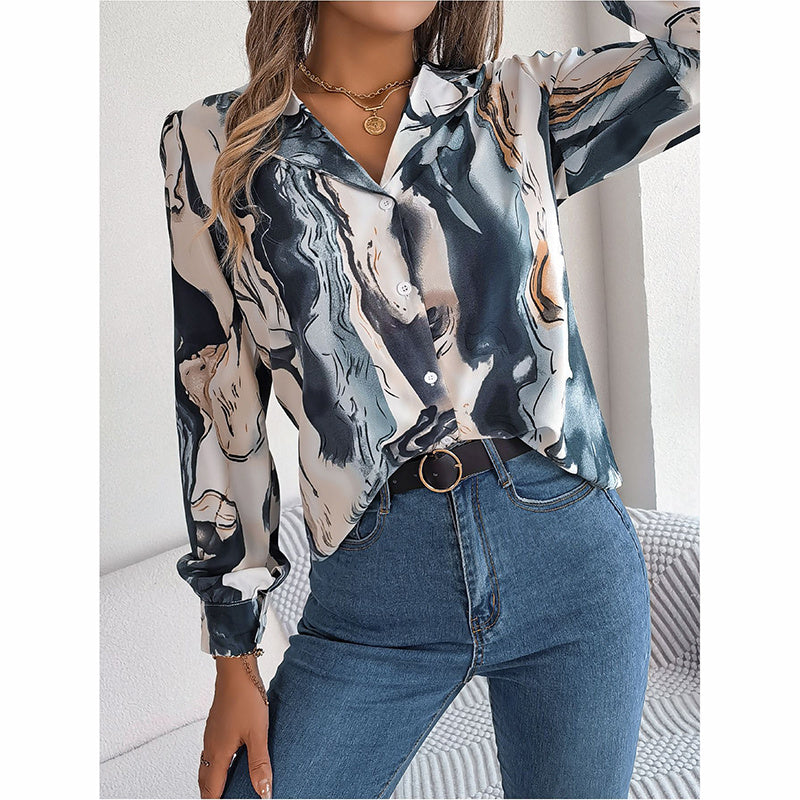 Person wearing a patterned blouse and jeans in a neutral setting