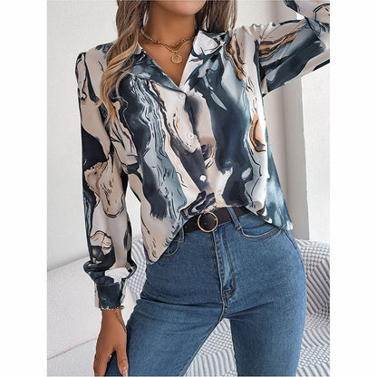 Person wearing a patterned blouse and jeans in a neutral setting
