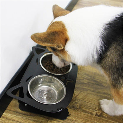 Cat drinking from a metal bowl on a black elevated pet feeder.