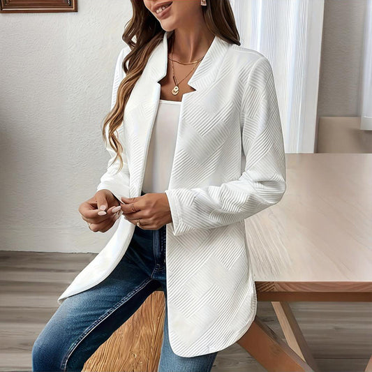 Woman wearing a white blazer over a white top and blue jeans indoors.