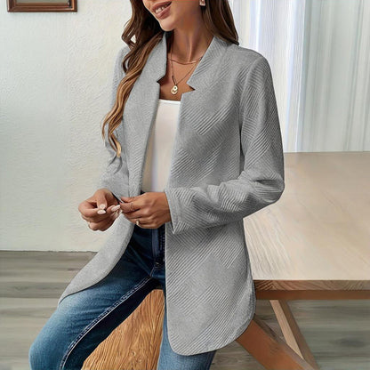 Woman wearing a gray cardigan over a white top and blue jeans in an indoor setting.