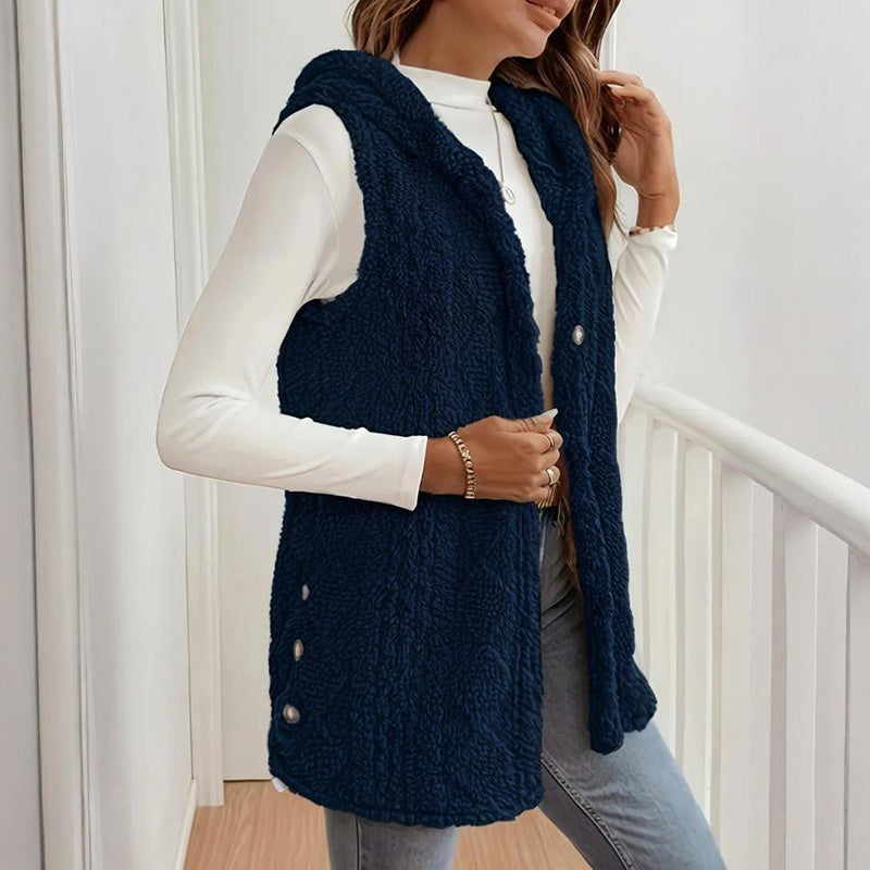 Person wearing a navy blue knitted vest over a white long-sleeve shirt.