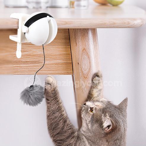 Cat playing with a dangling toy under a wooden table