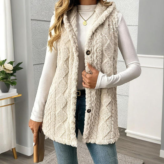 Person wearing a cream-colored cable knit vest with buttons indoors.