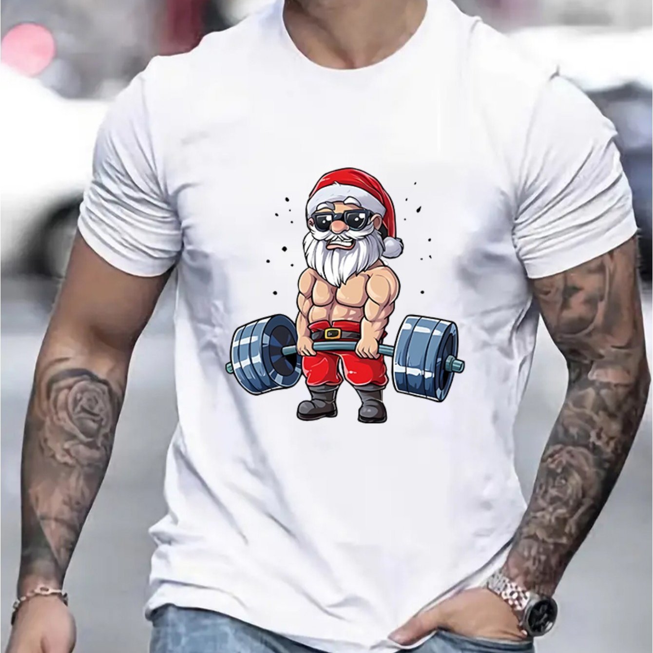 White t-shirt with a graphic of a muscular Santa Claus lifting weights, worn by a person.