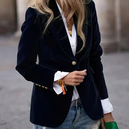 Person wearing a black blazer over a white shirt with a blurred background