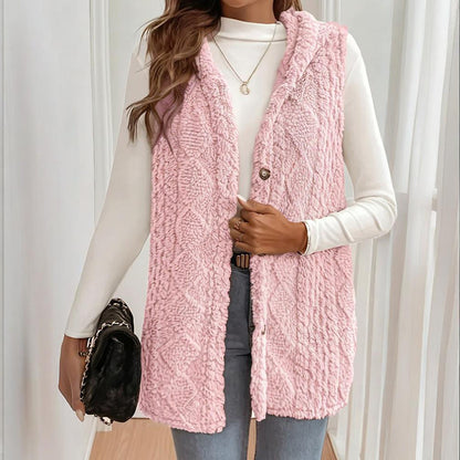 Person wearing a pink knitted vest over a white long-sleeve shirt.
