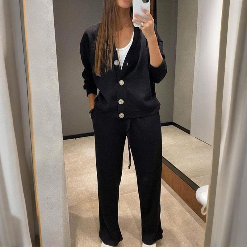 Person wearing a black outfit with white buttons in a mirror selfie.