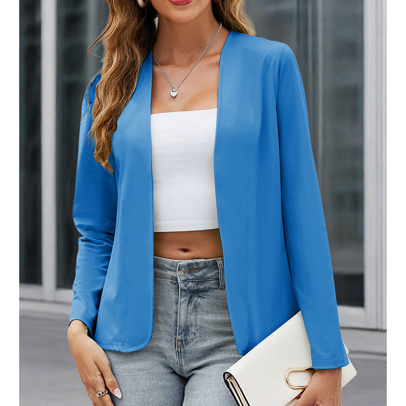 Woman wearing a blue blazer over a white top and jeans, holding a white clutch.