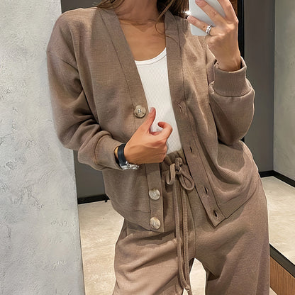 Person wearing a beige tracksuit taking a mirror selfie.