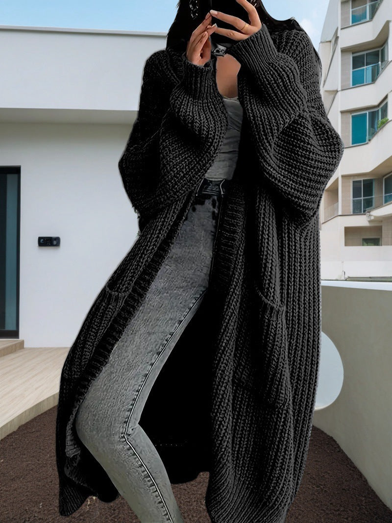 Person wearing a long dark gray knitted cardigan in an urban setting