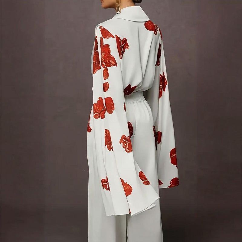 Person wearing a white outfit with red floral patterns on a dark background