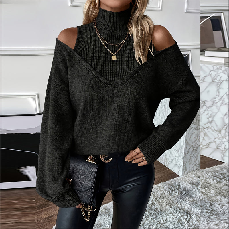 Person wearing a black off-shoulder sweater and black pants in an indoor setting.