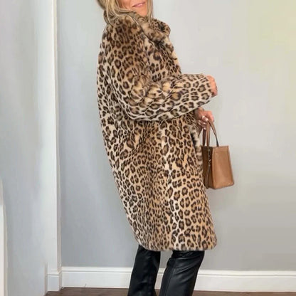 Person wearing a leopard print coat holding a brown handbag against a light blue wall.