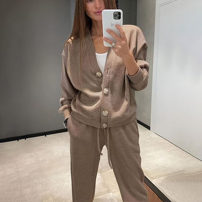 Woman taking a mirror selfie wearing a beige button-up top and pants.