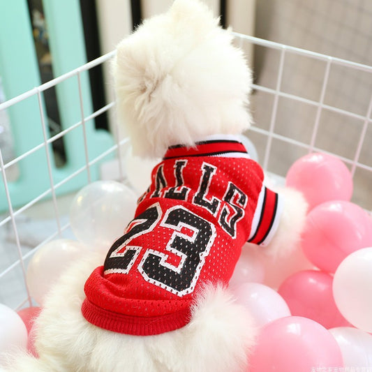 Dog wearing a red jersey with black text and numbers, surrounded by pink balloons.