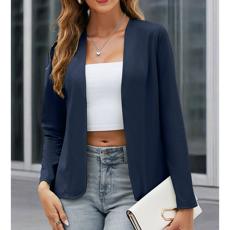 Woman wearing a navy blazer, white top, and jeans holding a clutch.