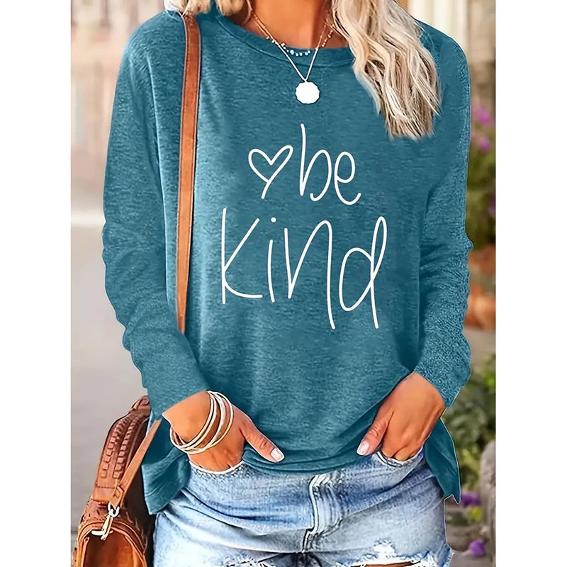 Blue sweatshirt with 'be Kind' text worn by a person outdoors.