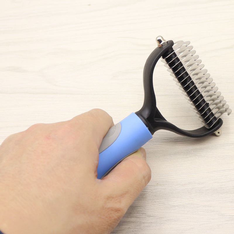 Hand holding a grooming tool with a blue handle on a light background