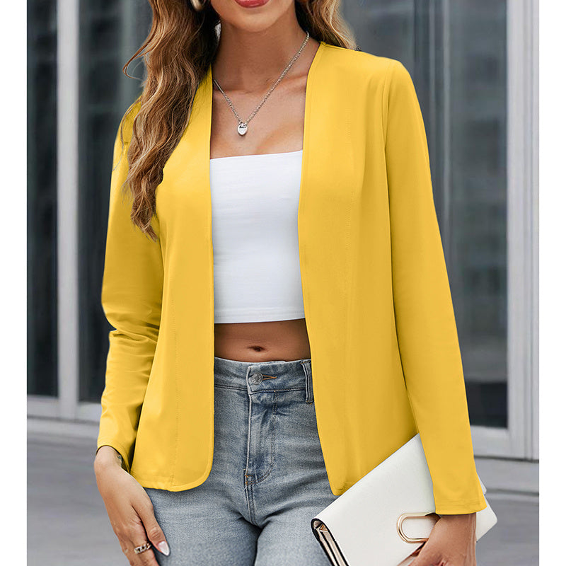 Woman wearing a yellow blazer over a white top and blue jeans, holding a white clutch.
