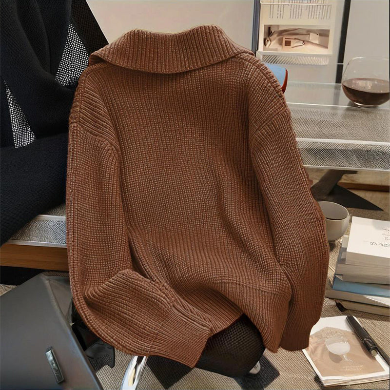 Brown sweater draped over a chair in an indoor setting with books and a cup on a table.