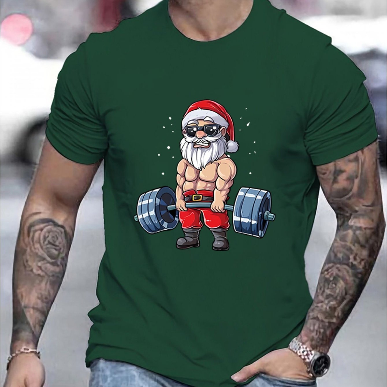 Green t-shirt with a graphic of Santa Claus lifting weights on a blurred background