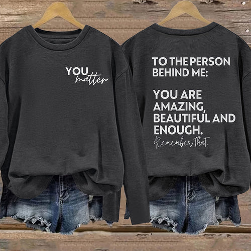Black sweatshirt with motivational message on front and back, worn by a person.