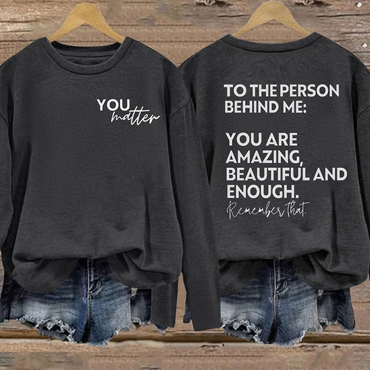 Black sweatshirt with motivational message on front and back, worn by a person.