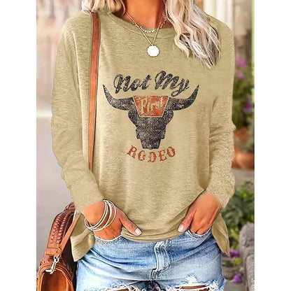 Person wearing a beige sweatshirt with a graphic design and text, standing outdoors.