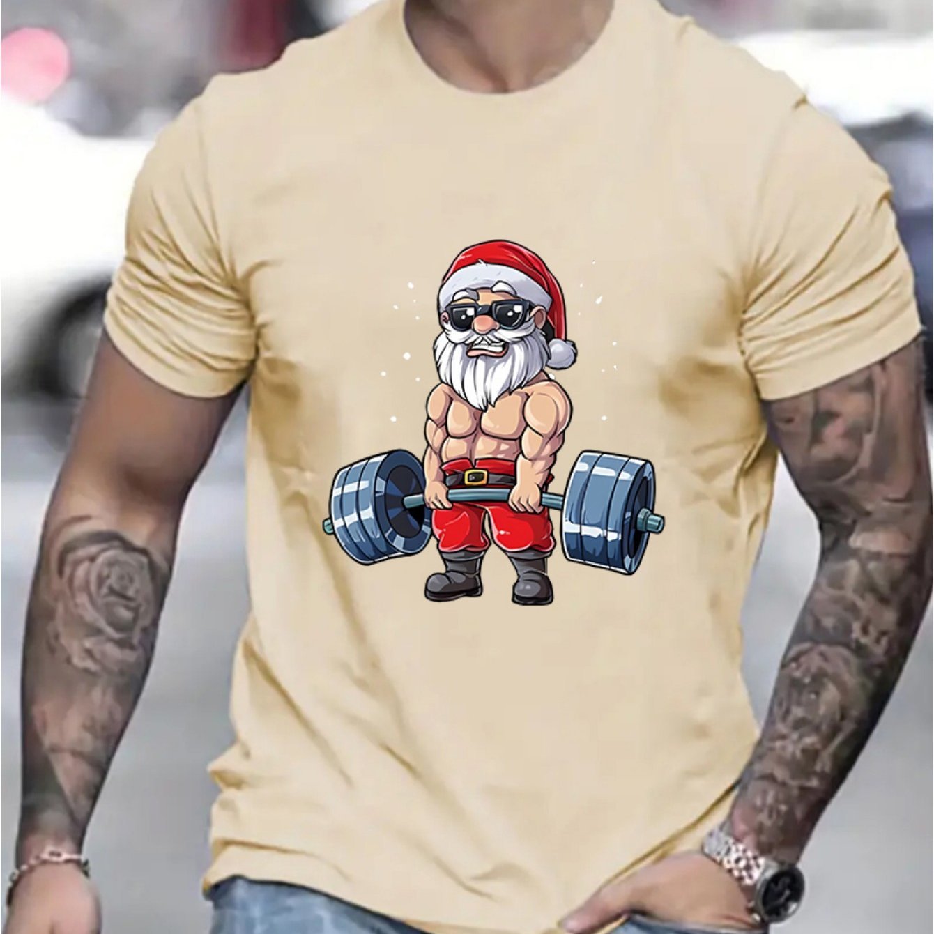 Beige t-shirt with a graphic of a muscular Santa Claus lifting weights.