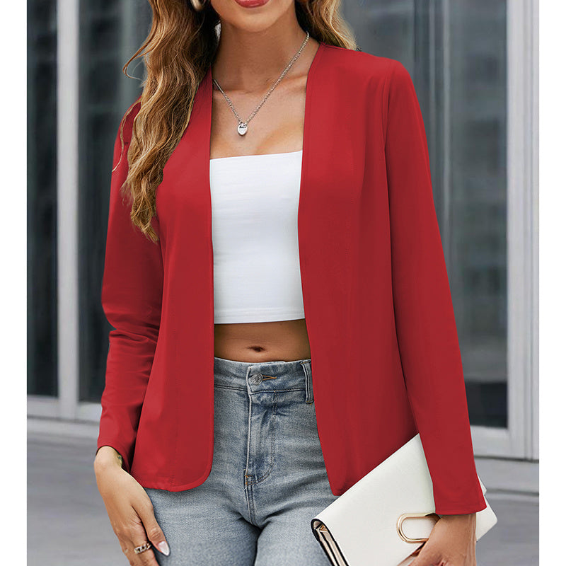 Woman wearing a red blazer over a white top and blue jeans, holding a white clutch.