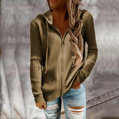 Person wearing a ribbed brown hoodie and ripped jeans against a neutral background