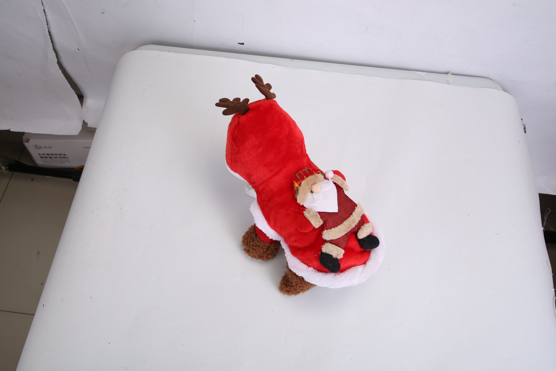 Red plush toy with a reindeer and Santa Claus design on a white surface.