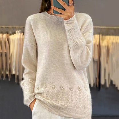 Person wearing a beige sweater with floral patterns in a clothing store.