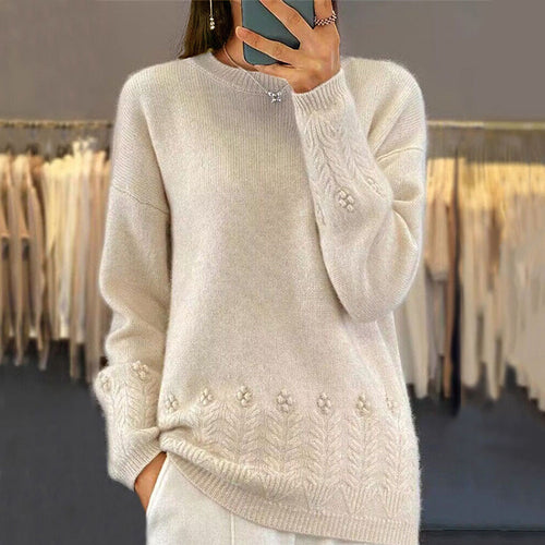 Person wearing a beige sweater with floral patterns in a clothing store.