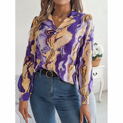 Woman wearing a purple and beige patterned blouse with blue jeans indoors.
