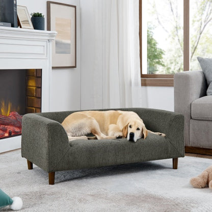 Dog lying on a gray pet bed in a cozy living room with a fireplace and sofa.