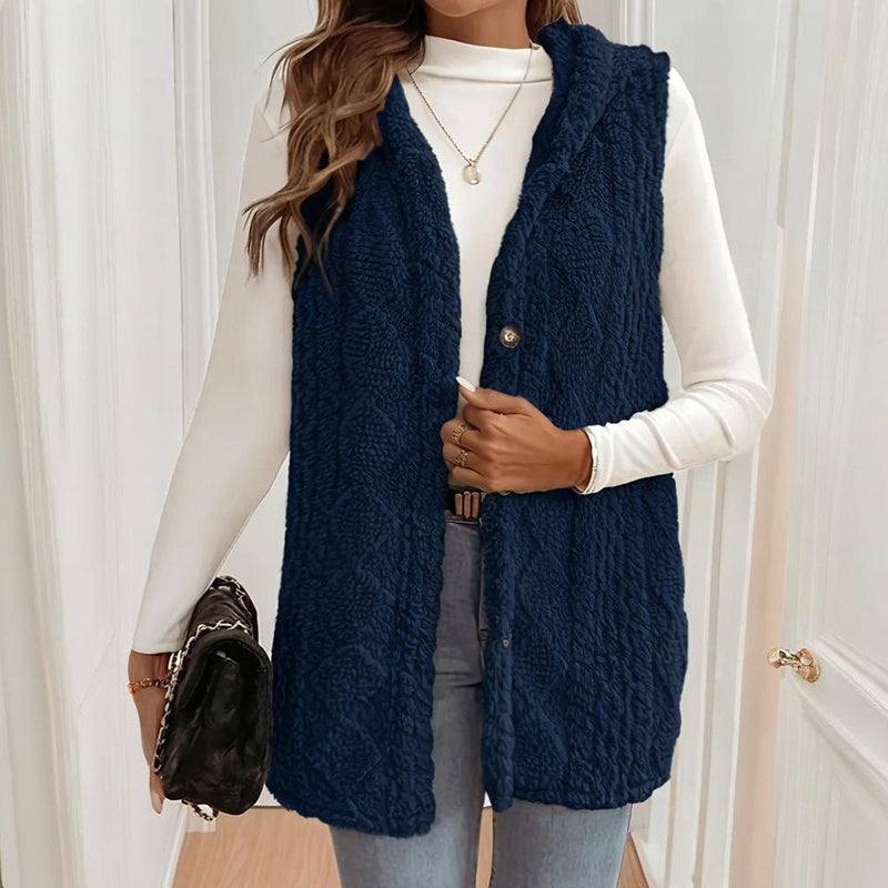 Person wearing a navy blue knitted vest over a white long-sleeve shirt.