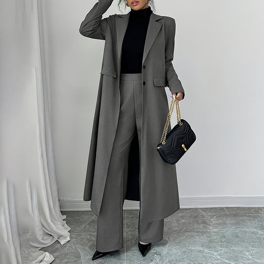 Person wearing a long gray coat and black pants, holding a black handbag against a plain background.