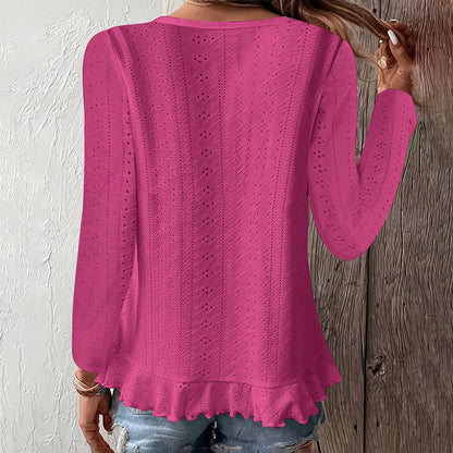 Pink knitted sweater worn by a person against a wooden and white wall.