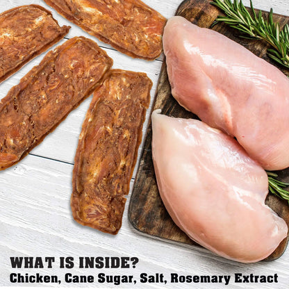 Raw chicken breasts and dried meat slices on a wooden board with rosemary, on a white wooden surface.