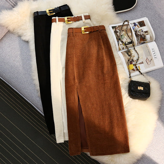 Brown skirt with black, white, and beige skirts on a textured surface with a magazine and handbag.