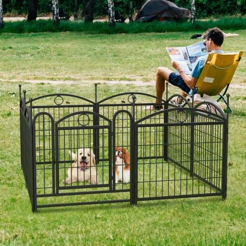 Two dogs in a black metal pet pen with a person reading a newspaper in the background.